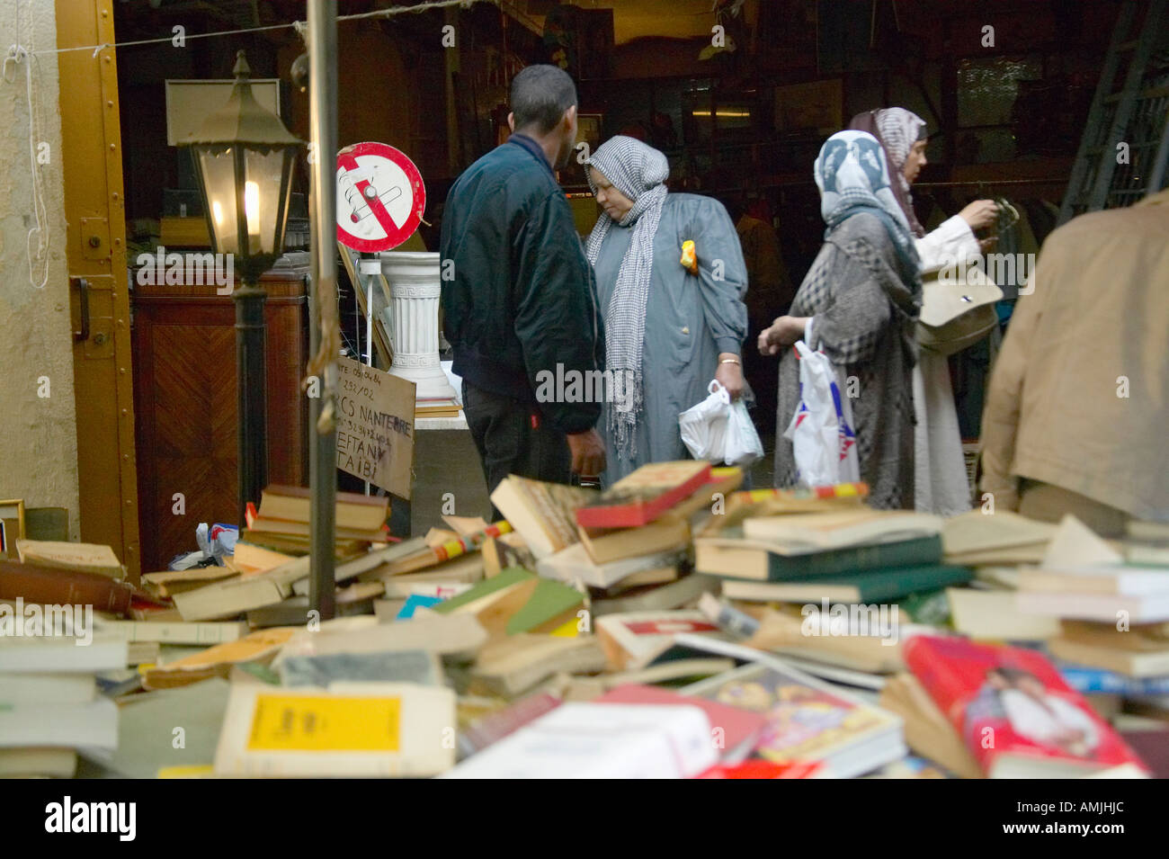 Bücher zum Verkauf an Flohmarkt muslimische Frau und der Mann im Hintergrund Paris Frankreich Stockfoto