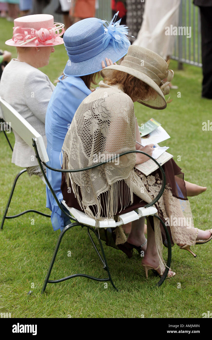 Frauen sitzen auf einer Bank am Royal Ascot Pferderennen, York, Großbritannien Stockfoto