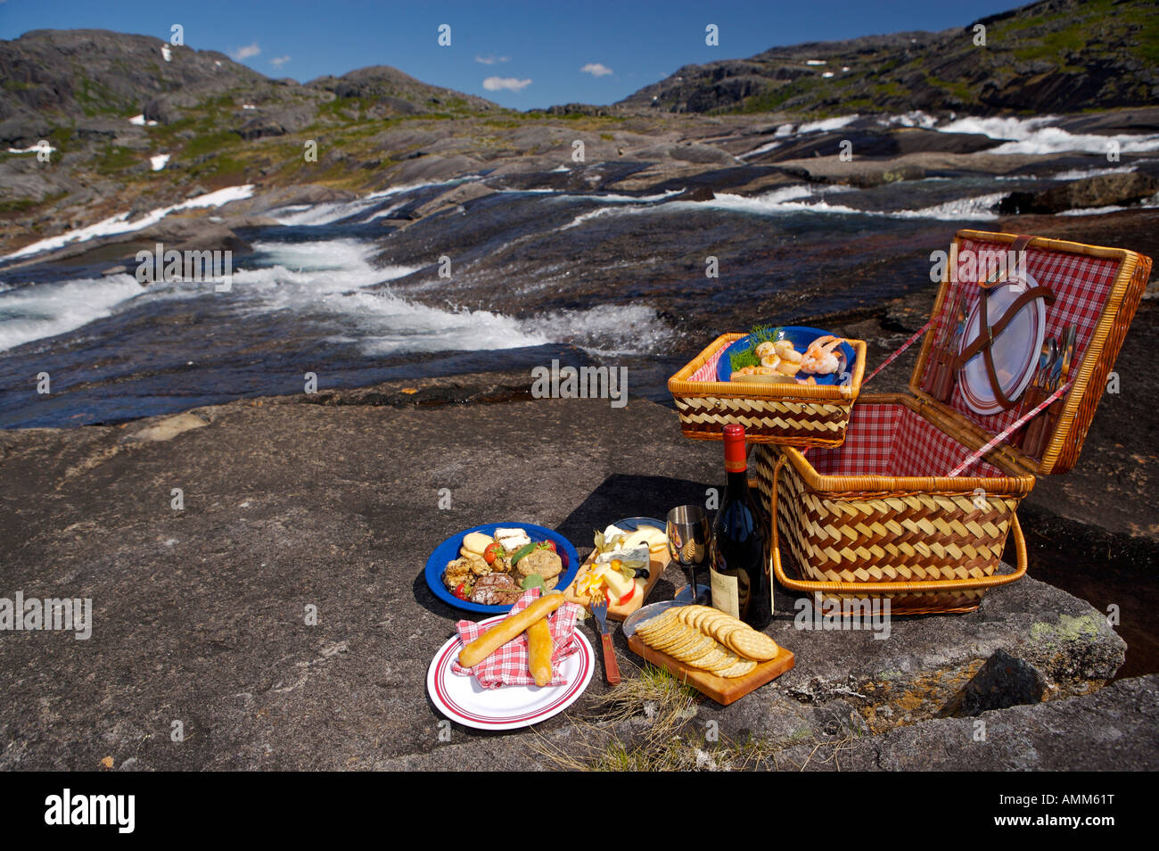 Picknickkorb neben einem Wasserfall mit einem Hubschrauber im Hintergrund in den Bergen Mealy, Neufundland und Labrador, Kanada. Stockfoto