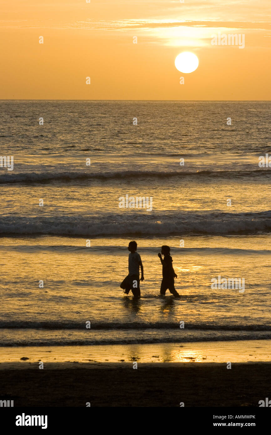 Paare, die auf Kuta Strand bei Sonnenuntergang Stockfoto