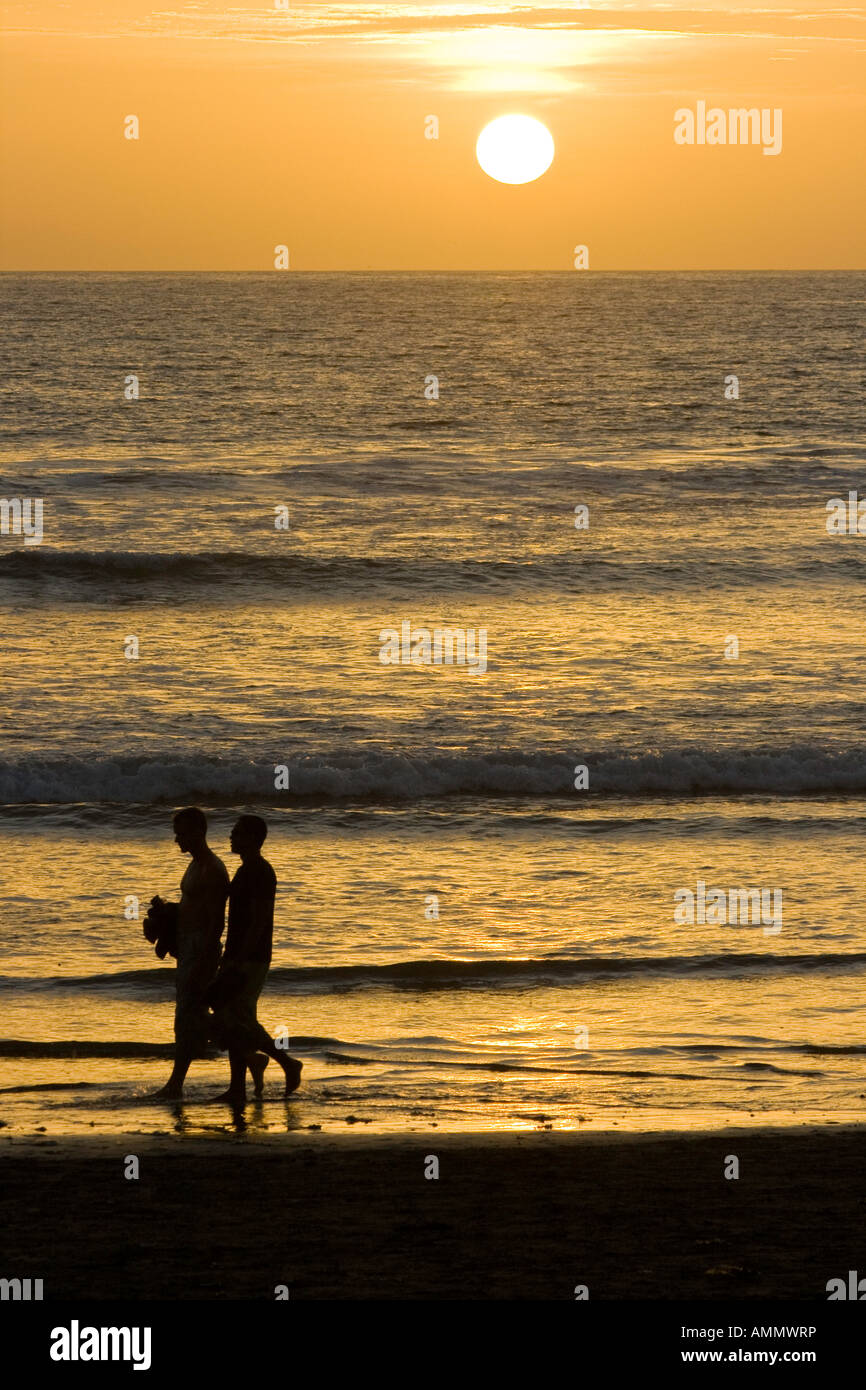 Paare, die auf Kuta Strand bei Sonnenuntergang Stockfoto
