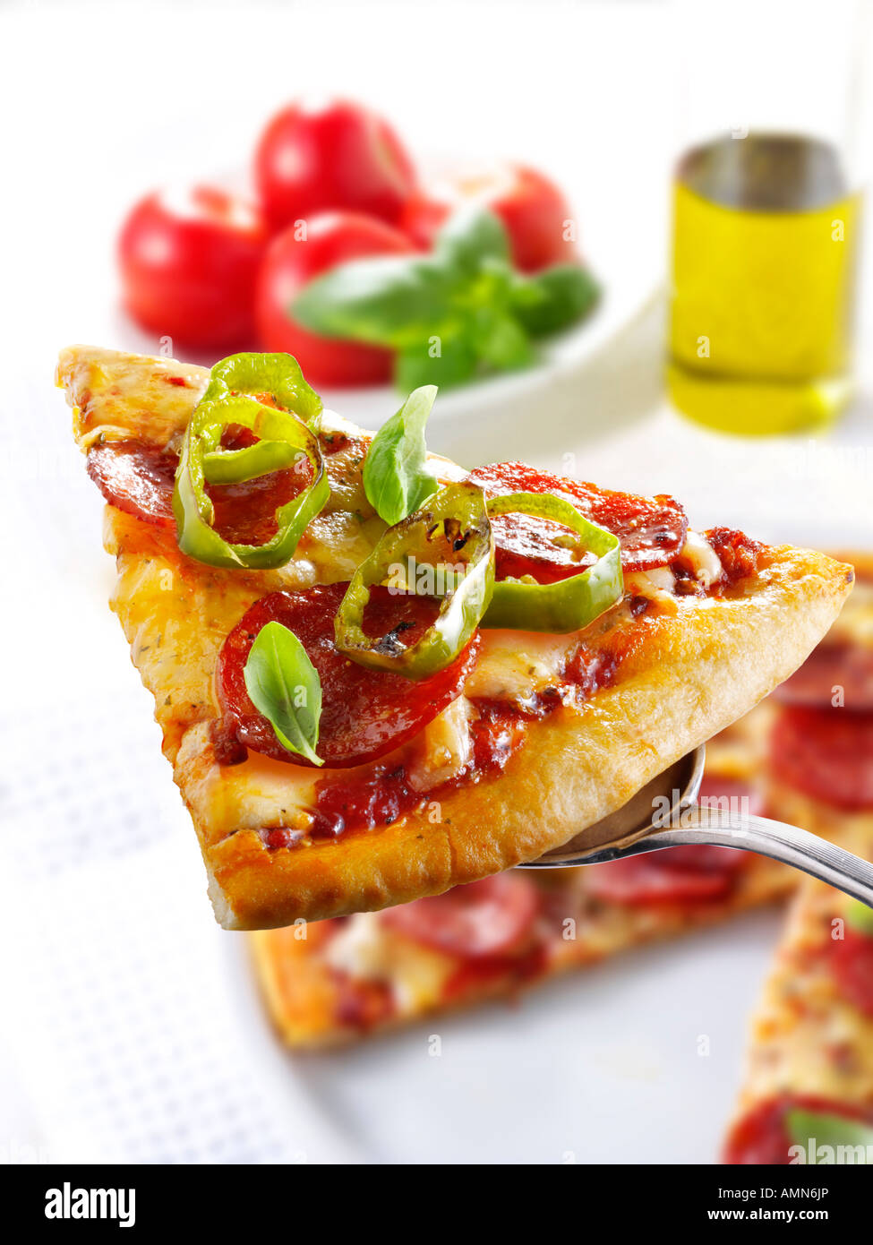 Pizzastück belegt mit Salami und Chili Stockfoto