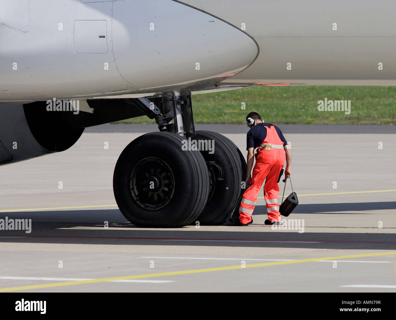 Mitglied des Bodenpersonals sichern das Fahrwerk eines Flugzeugs Stockfoto