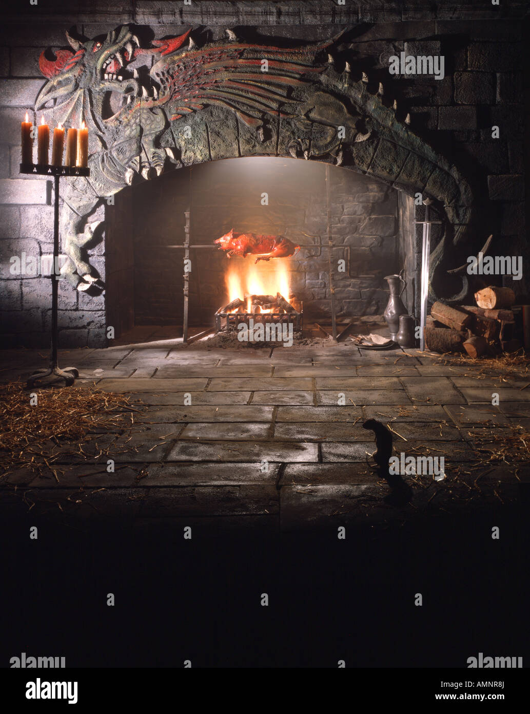 Sankt-Georgs Tag in einer mittelalterlichen Burg mit Spanferkel braten über offenem Kamin mit einem schnitzen eines Drachen darüber. Stockfoto