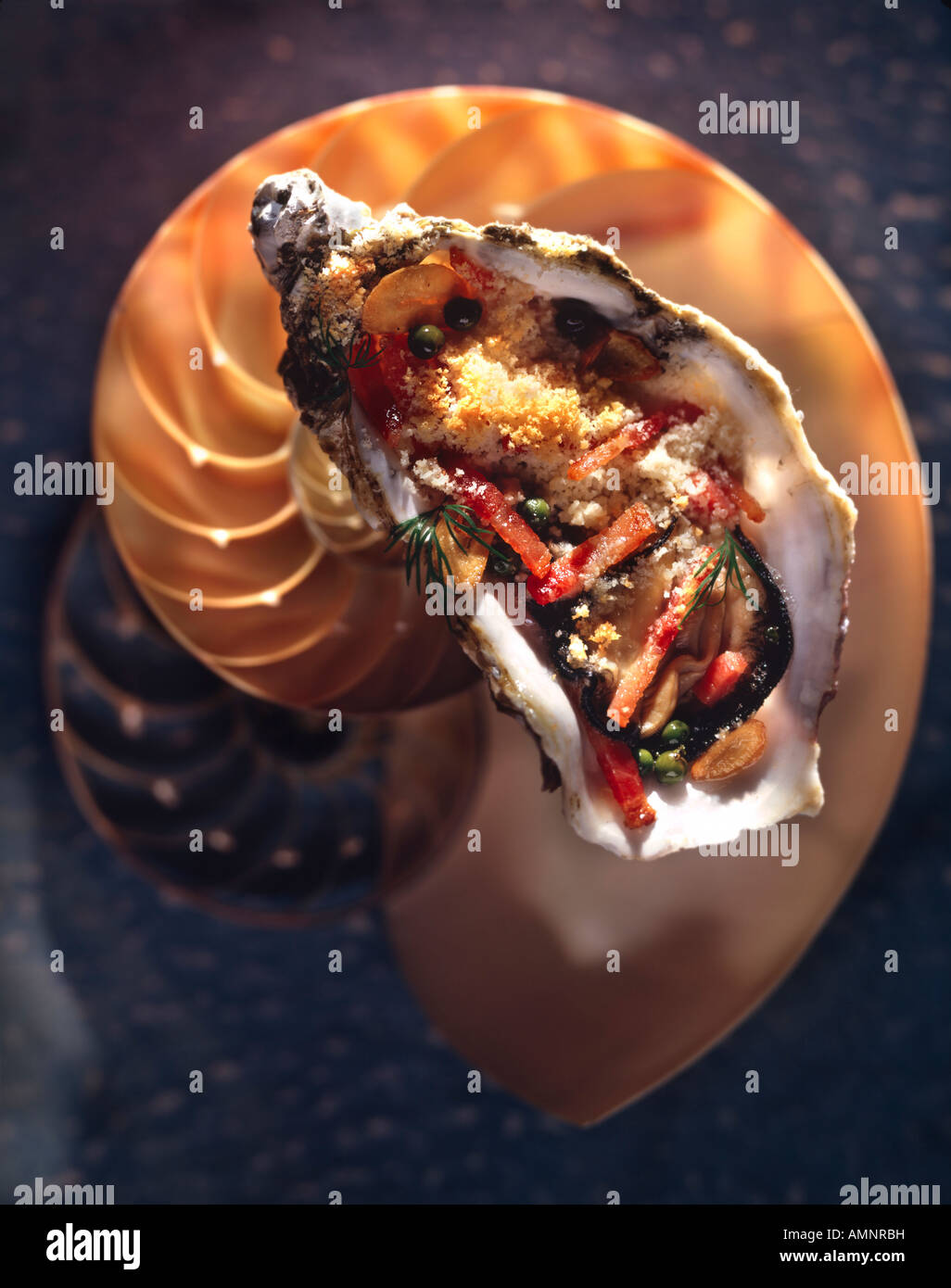 Gegrillte Austern garniert mit Julienne von Carot, in der Schale mit einem Shell-Hintergrund Stockfoto