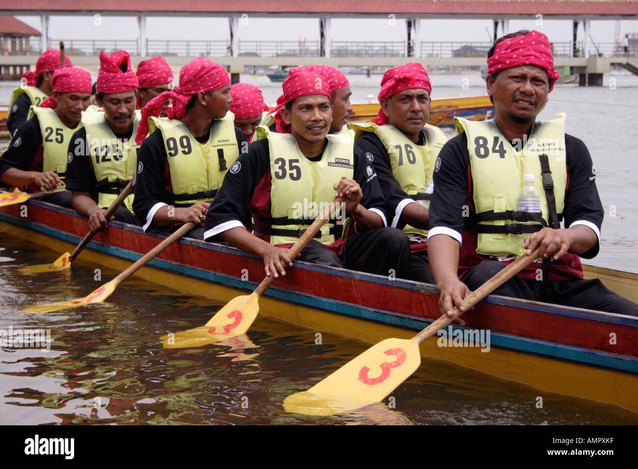 Die Ruderer mit bunten Kopf Gang in einem traditionellen malaiischen lange Boot in Kuala Terengganu, Malaysia Stockfoto