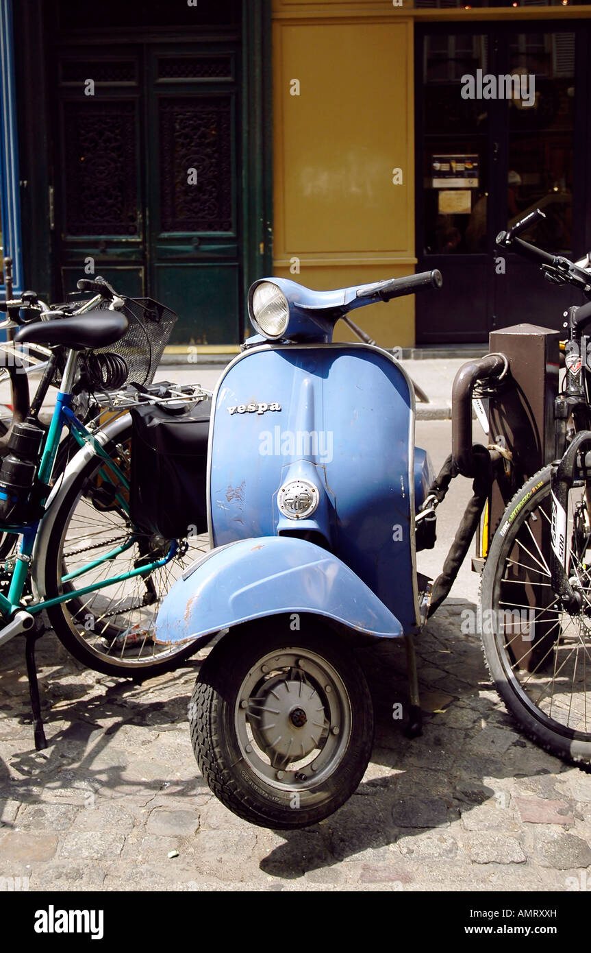 Alte blaue Vespa mit dinted Schutzblech und Kratzer geparkt zwischen Fahrräder auf den Straßen von Paris Stockfoto