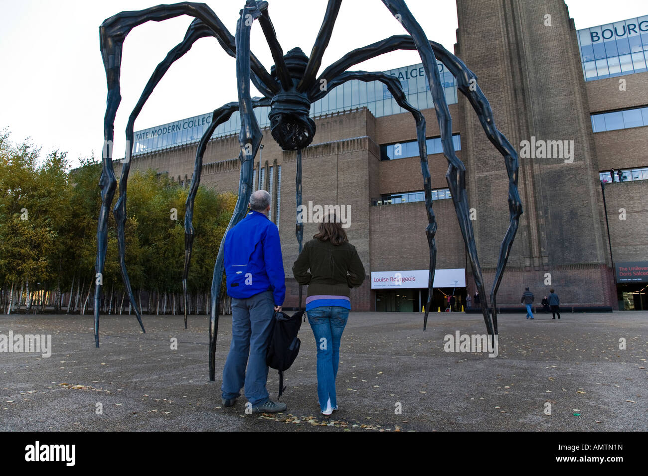 Besucher sehen die Bronzeskulptur Maman von Louise Bourgeois außerhalb der Tate Modern, London, England. Stockfoto