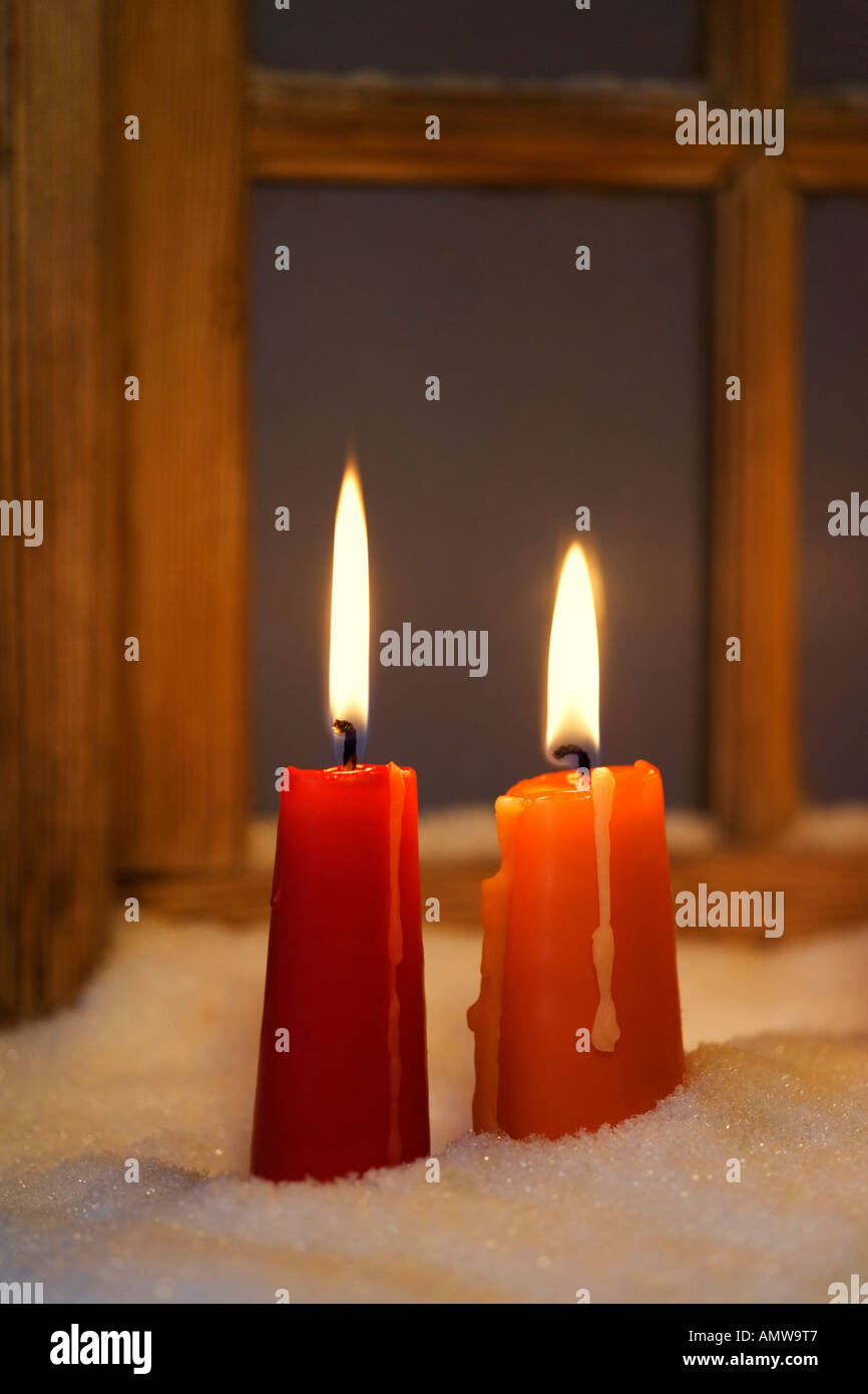 Zwei brennende Kerzen im Schnee vor einem alten Fenster Stockfotografie -  Alamy