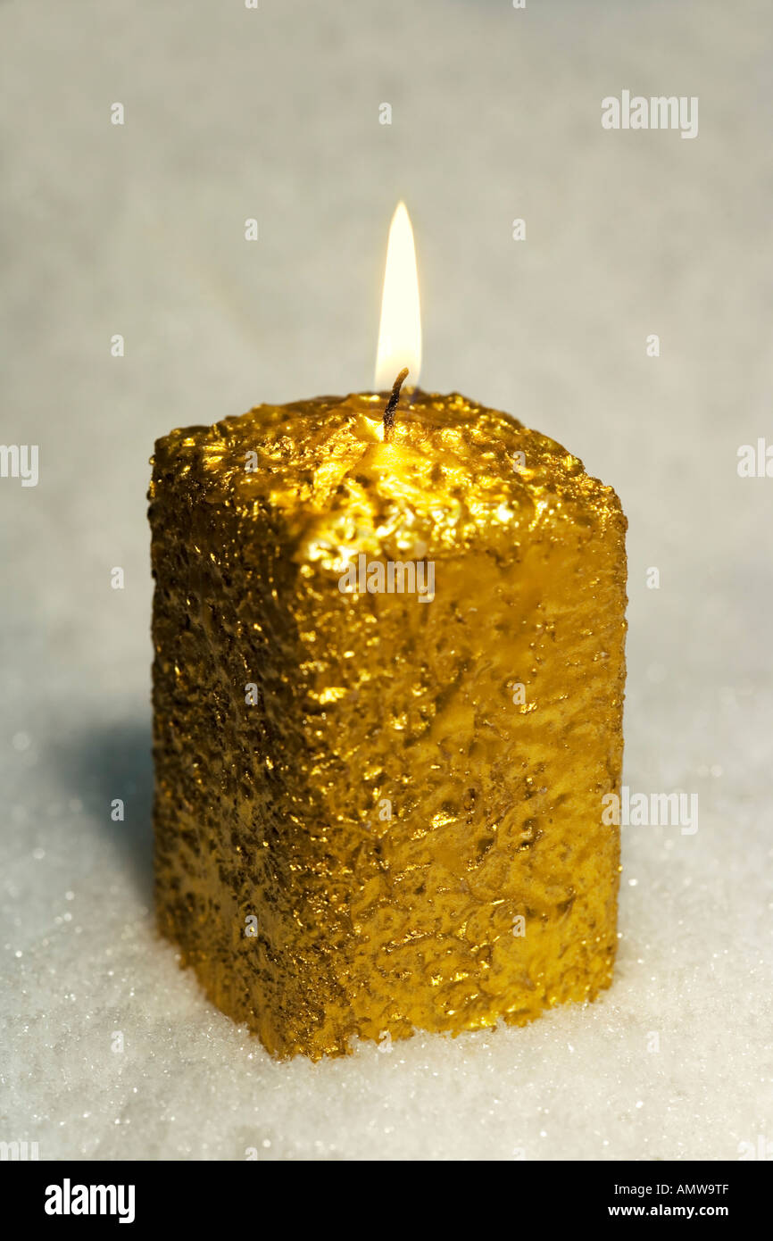 Brennende Goldene Kerze im Schnee Stockfoto