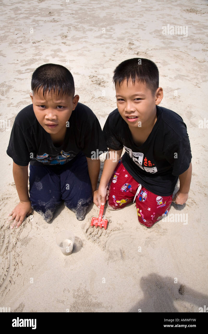 Jungs, die versuchen, kleine Krabben in Sattahip Beach in der Nähe von Rayong Thailand zu sammeln Stockfoto