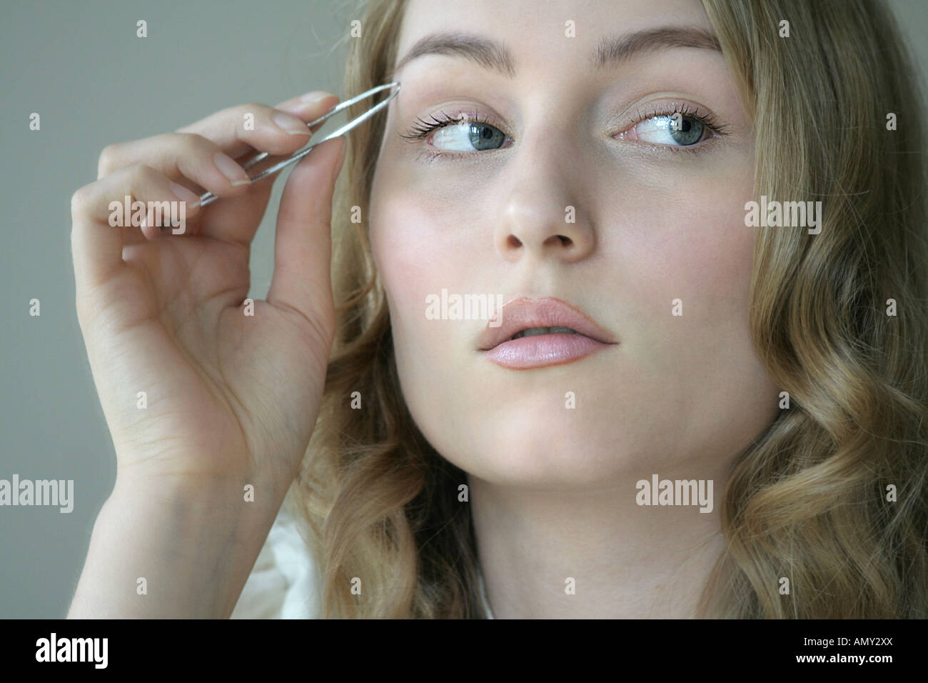Reflexion der jungen Frau mit Augenbrauen Pinzette Stockfoto