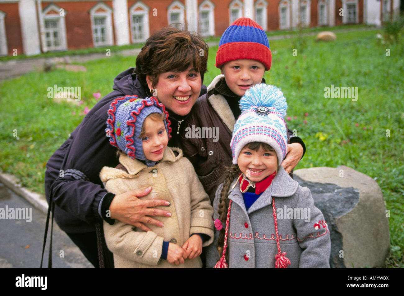 Drei süße junge russische Kinder mit ihren Müttern im Innenhof einer alten russischen orthodoxen Kirche Stockfoto