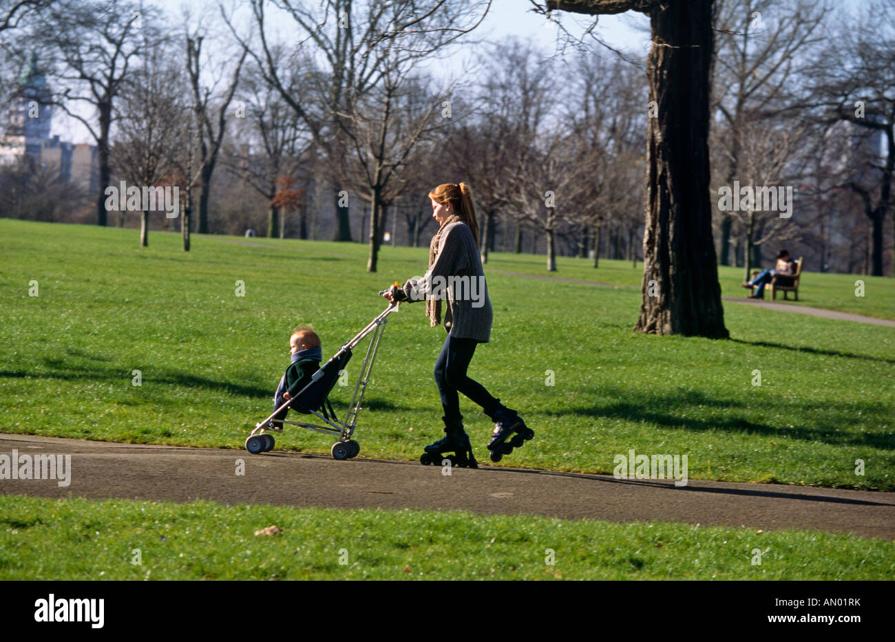 MDCHEN DRCKT KIND IM KINDERWAGEN AUF ROLLER-BLADES Stockfotografie - Alamy