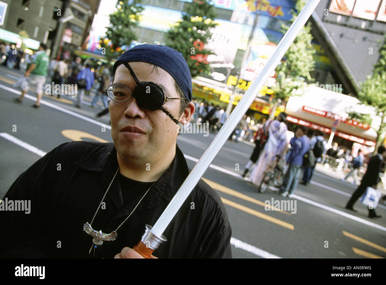 Ein Mann trägt eine Augenklappe und tragen ein Lichtschwert auf einer Straße in Akihabara in Tokio, Japan Stockfoto
