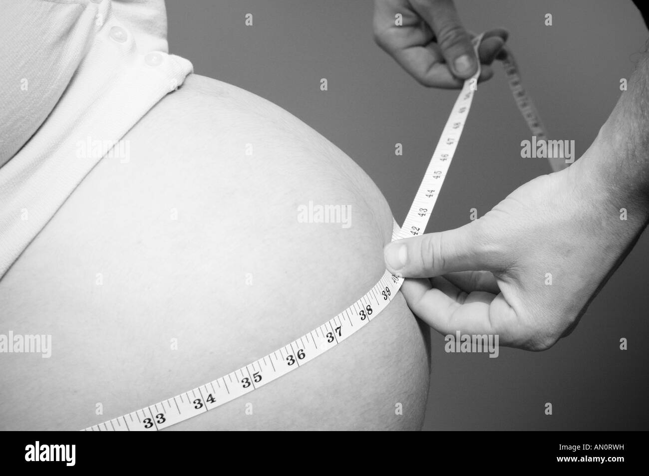 Schwangere Frau mit einem Mann, Verlobter, Freund oder Ehemann messen ihren Bauch, Mittelteil Stockfoto