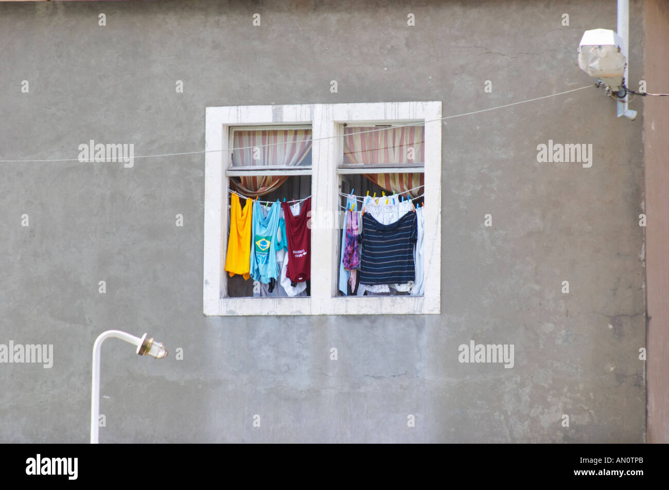 Ein Fenster mit Wäscheleinen, die Wäsche zum Trocknen aufhängen. Weiße  Fensterrahmen, graue Wand, bunte Kleidung. In Kamenari. Montenegro, Balkan,  Europa Stockfotografie - Alamy