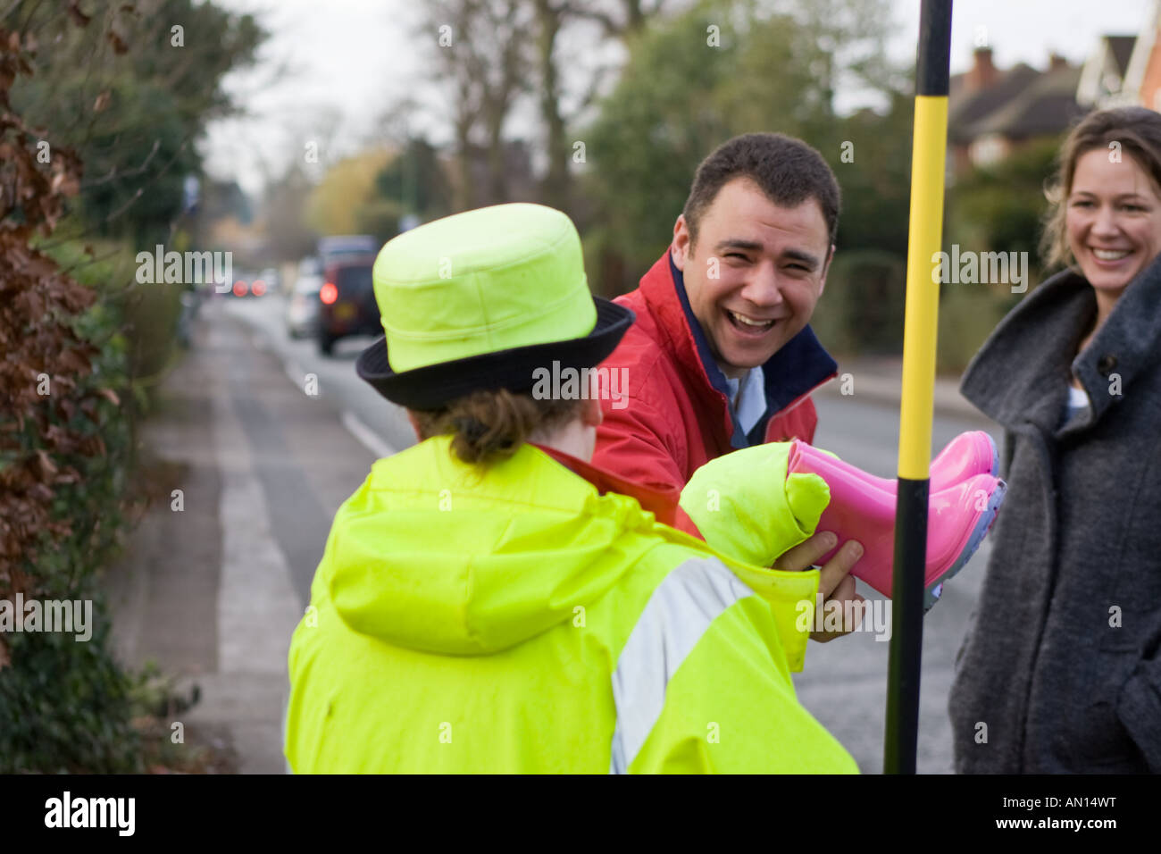 Britische "Lollipop Lady" hilft, ein Mann und eine Frau die Straße überqueren Stockfoto
