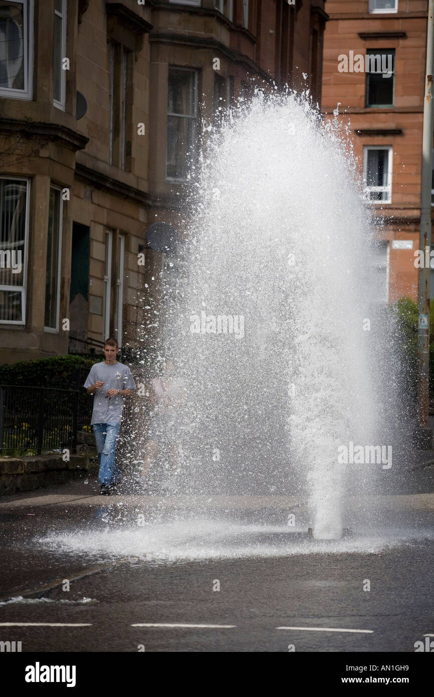 Ein Wasser-Hydrant platzen und sprudelt Wasser in einer Straße in Dennistoun Glasgow UK Stockfoto