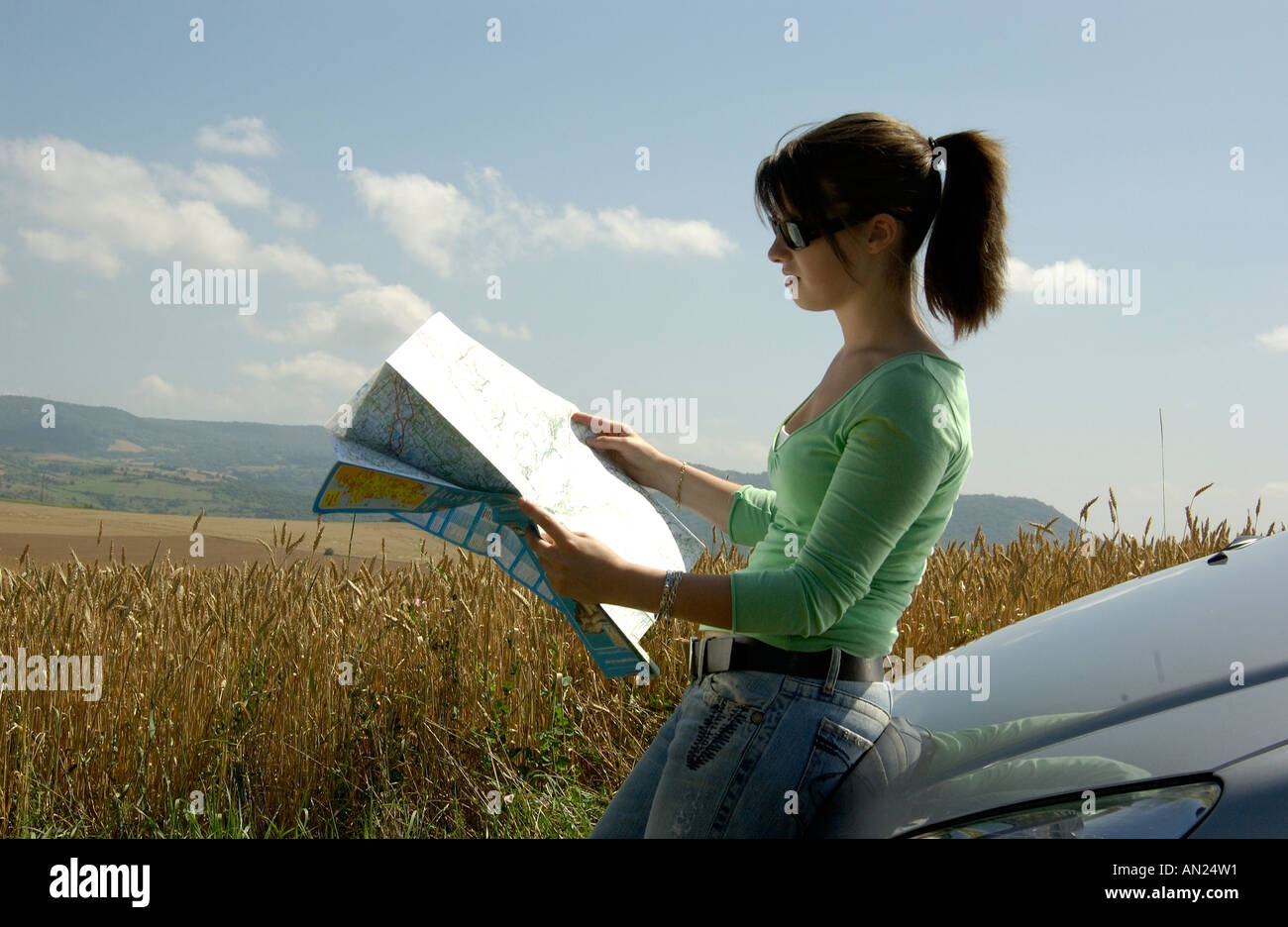 Junge Frau Treiber Blick auf eine Karte, verloren in der Landschaft im Sommer Stockfoto