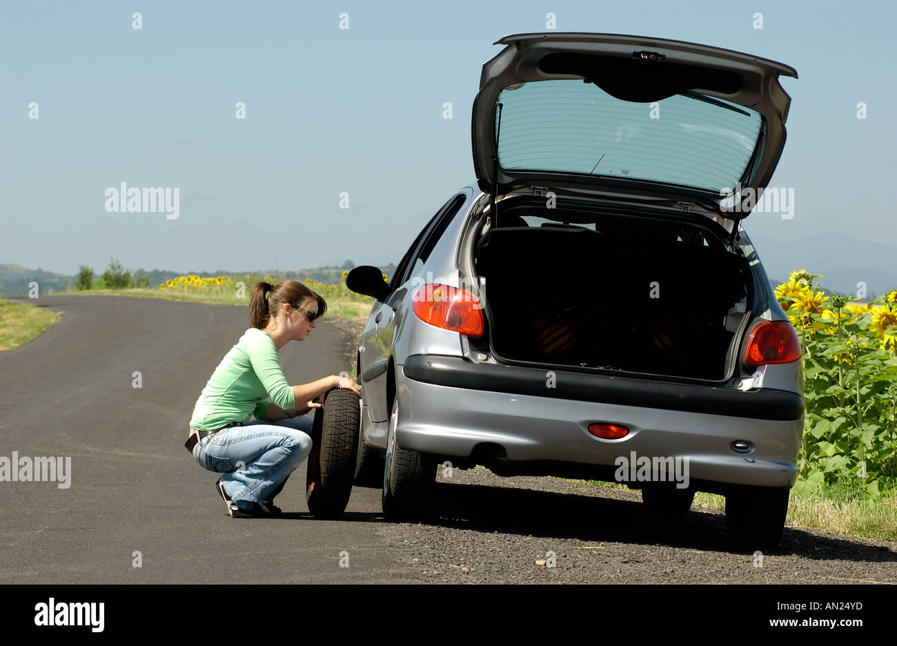 Frau mit einem Platten Reifen auf ihrem Auto Radwechsel geparkt am Straßenrand im Land Stockfoto