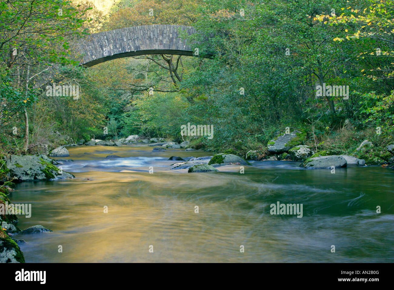 historische Brücke über River mit herbstlichen Farbe Reflexionen an Watersmeet Watersmeet Exmoor National Park Devon England UK Stockfoto