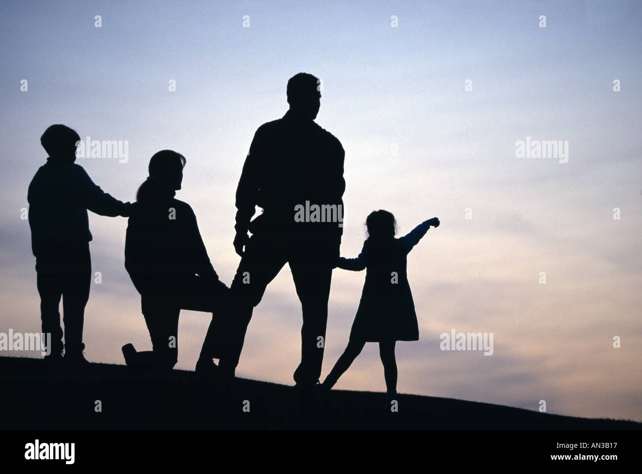 Silhouette der Familie auf dem Hügel beobachten Abendhimmel Stockfoto