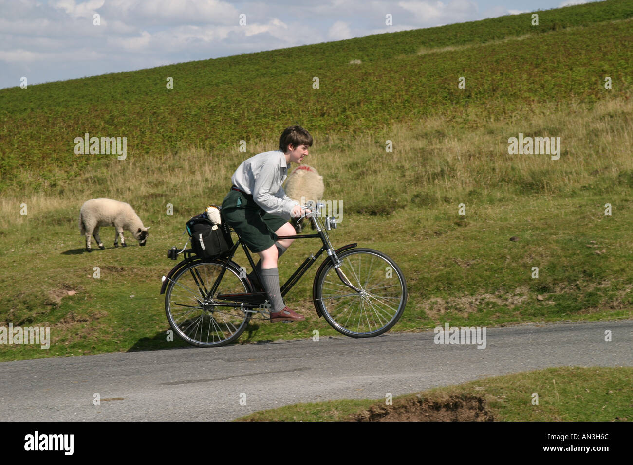 Junge Frau mit einem altmodischen Fahrrad reitet auf einem steilen Hügel auf Dartmoor Stockfoto