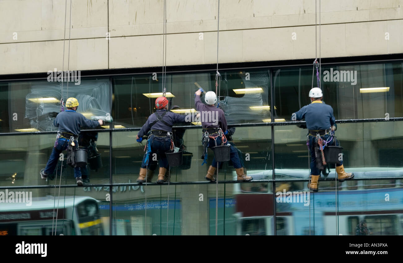 Fensterputzer hängen vor einer Gebäudefassade Stockfoto