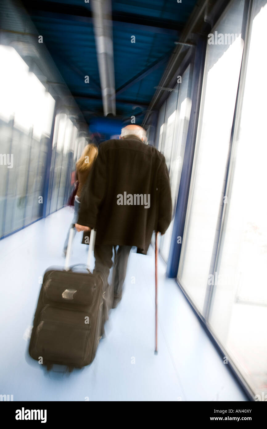 Alter Mann zeichnen einen Roller Koffer durch eine Flughafen-Korridor Stockfoto