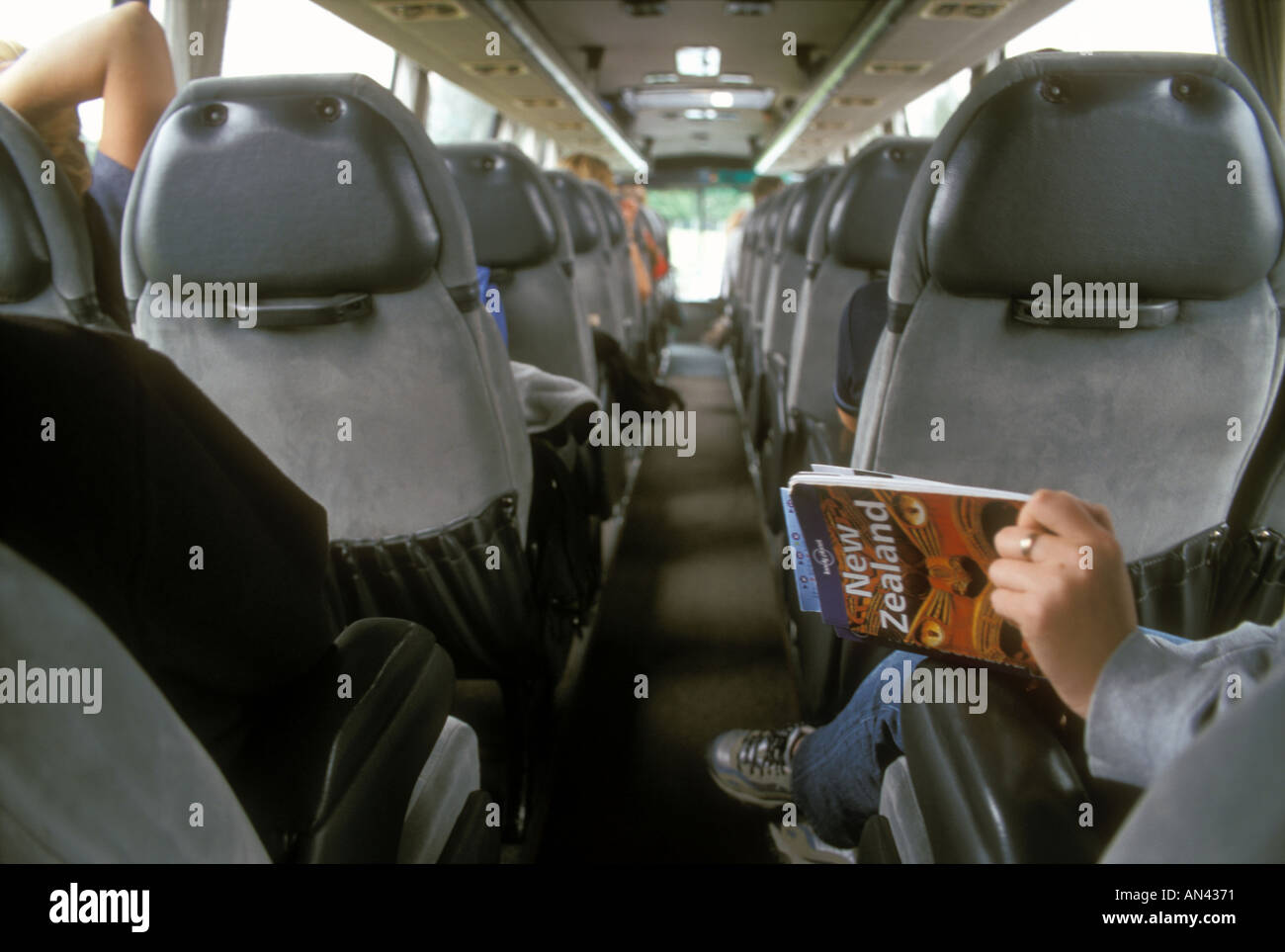 Ein Reisender liest der Lonely Planet Reiseführer auf einen Bus in Neuseeland Stockfoto