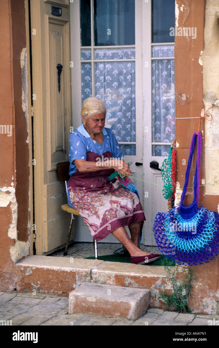 Frau macht traditionelle Handwerke vor ihrem Haus in Marsaxlokk, Malta Stockfoto