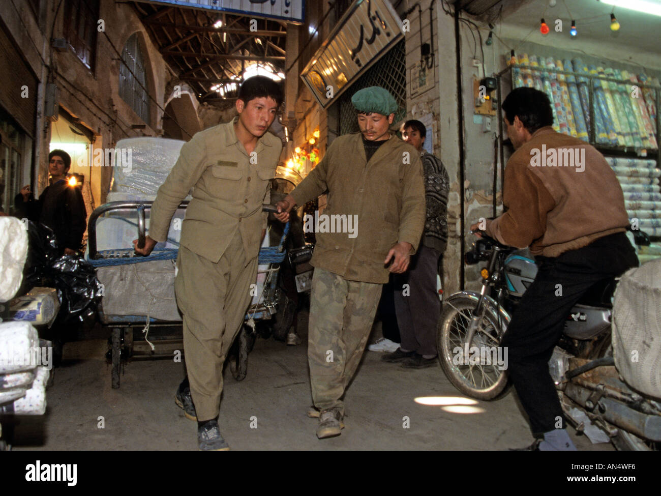 Männer stark ziehen beladene Karre entlang Gasse im Basar, Teheran, Iran Stockfoto