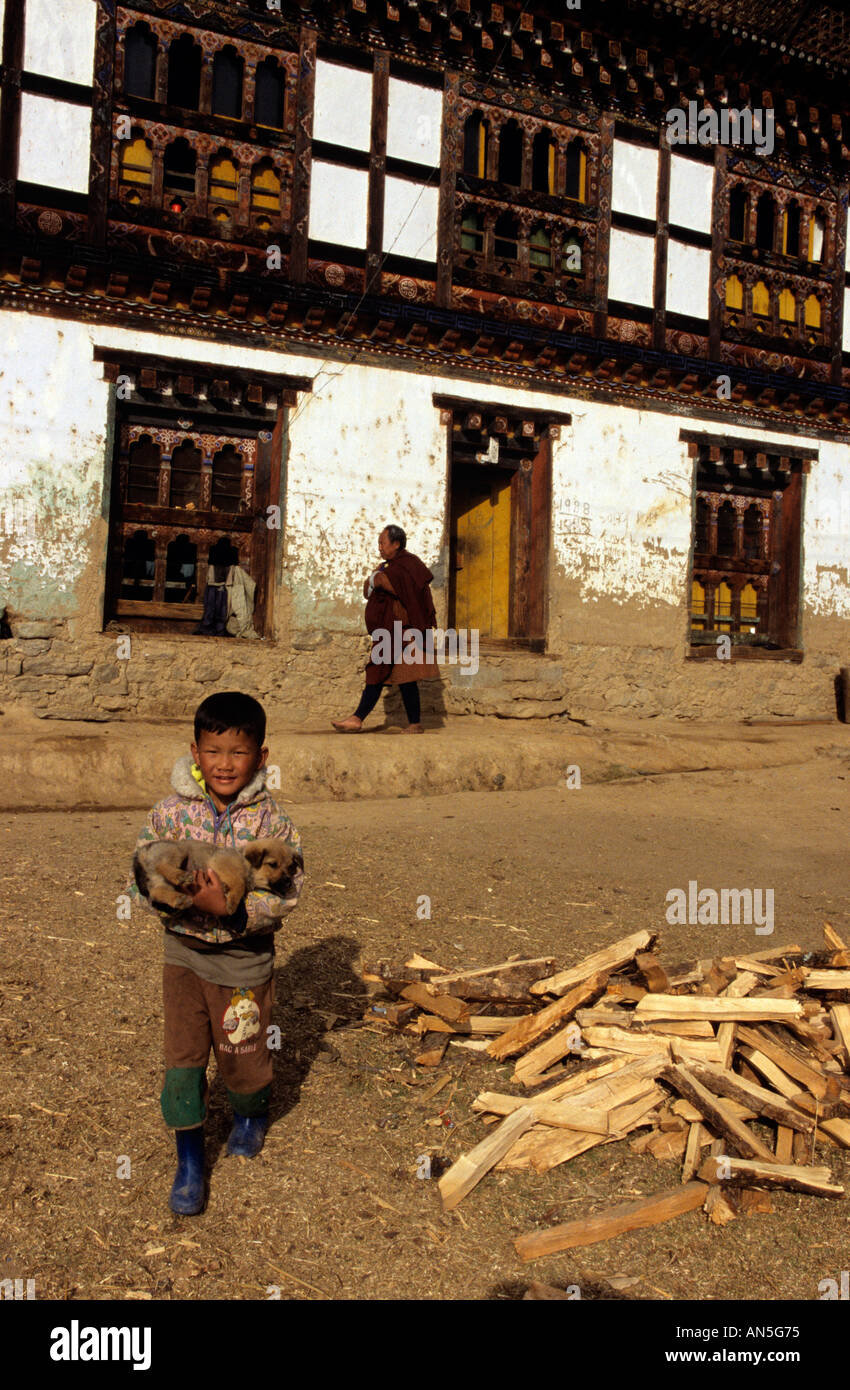 Ein Junge trägt einen Hund außerhalb eines Klosters in Bhutan Stockfoto