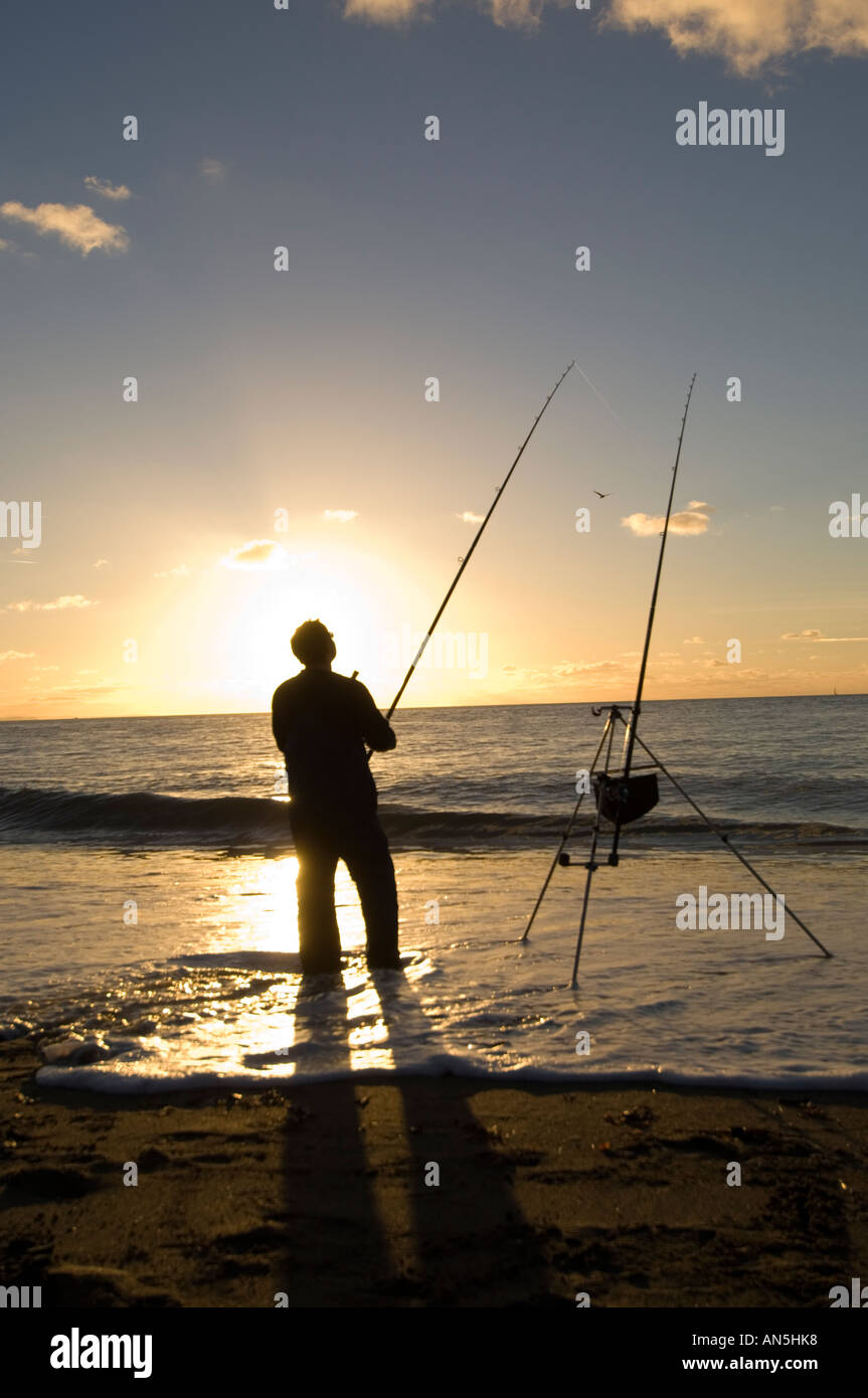 Silhouette der Mann Angeln mit zwei Ruten in Meer Aberystwyth Südstrand, Sommerabend bei Sonnenuntergang Stockfoto