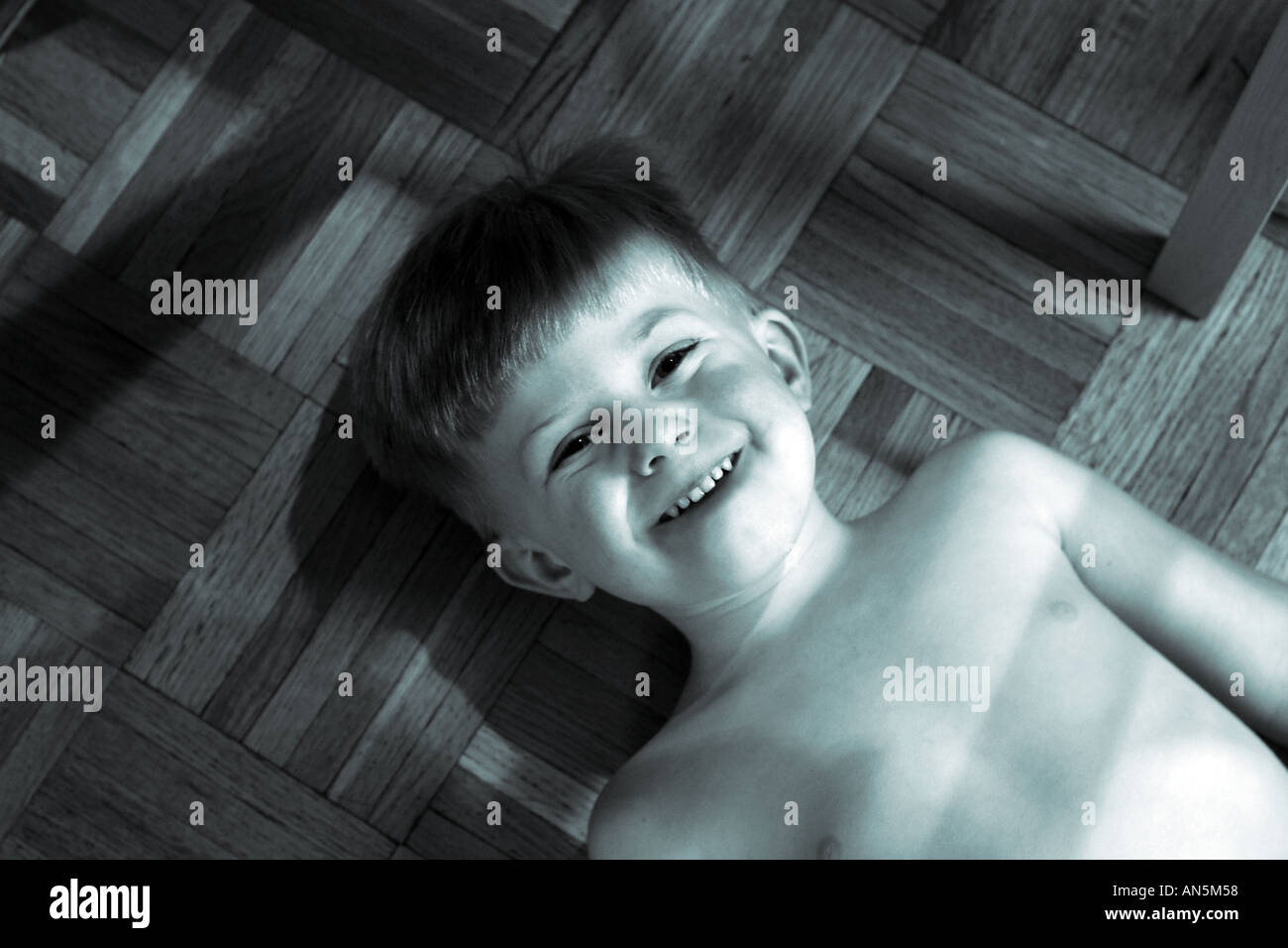 Kleiner Junge macht ein lustiges Gesicht für die Kamera Lächeln und getönten Cyan und Schwarz spielen Stockfoto