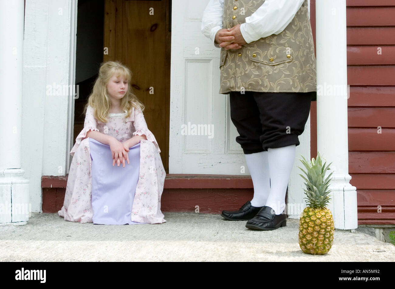 Kleine Mädchen und Mann mit 18. Jahrhundert Kleidung vor einem historischen Haus im Kolonialstil mit Ananas Stockfoto