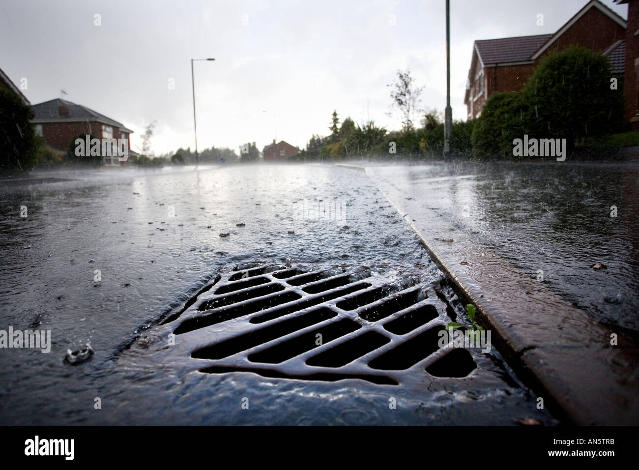 Regenwasser fließt in einen Abfluss an der Seite einer Straße in Redditch, Worcestershire UK während einem Sommergewitter Stockfoto