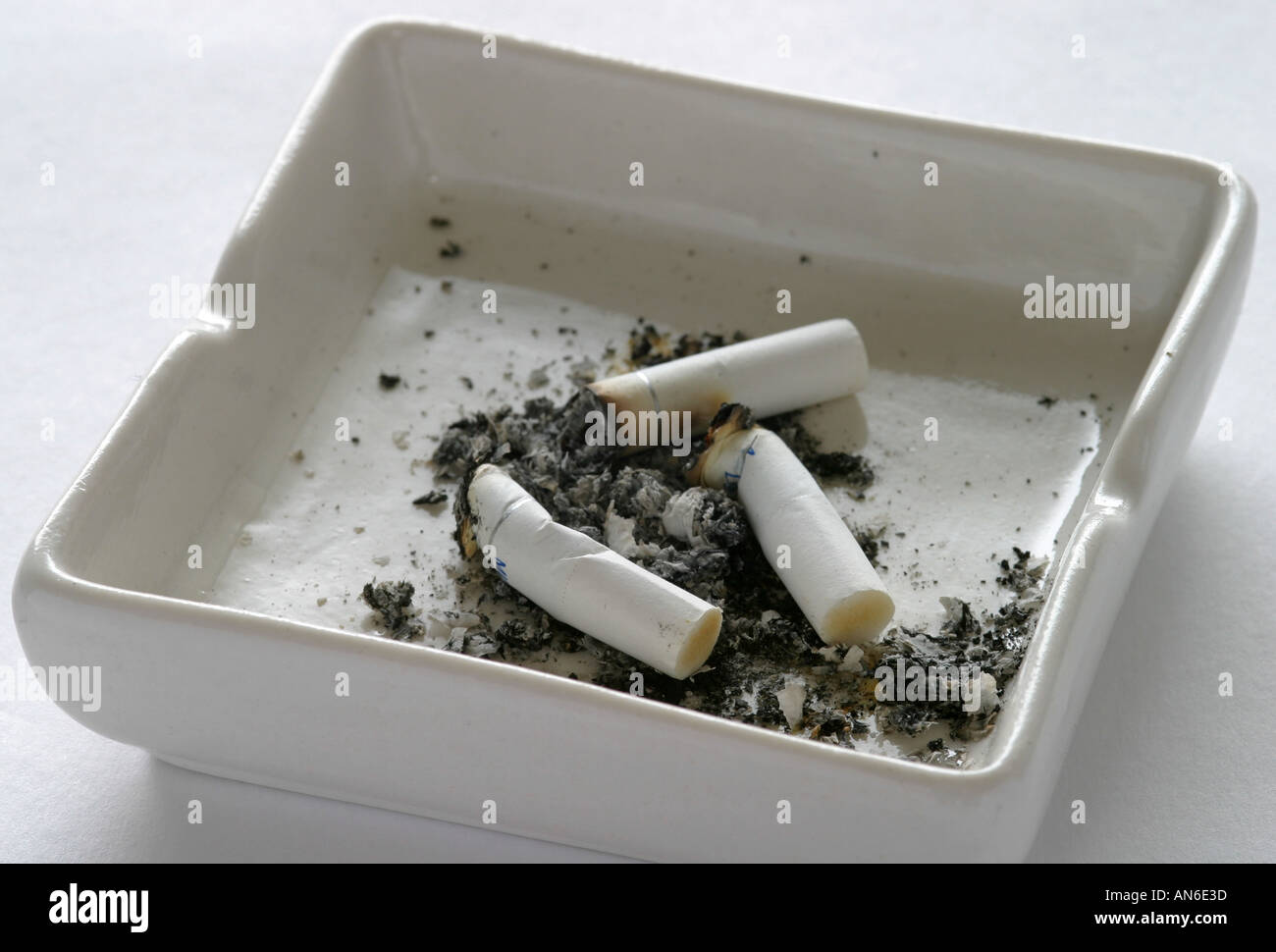 Alten abgestandene Zigaretten verworfen in schlichte weiße Aschenbecher mit schmutzigen Asche und Überreste von Gesundheit Problem Rauchverbot anti-Rauchen-fag Stockfoto