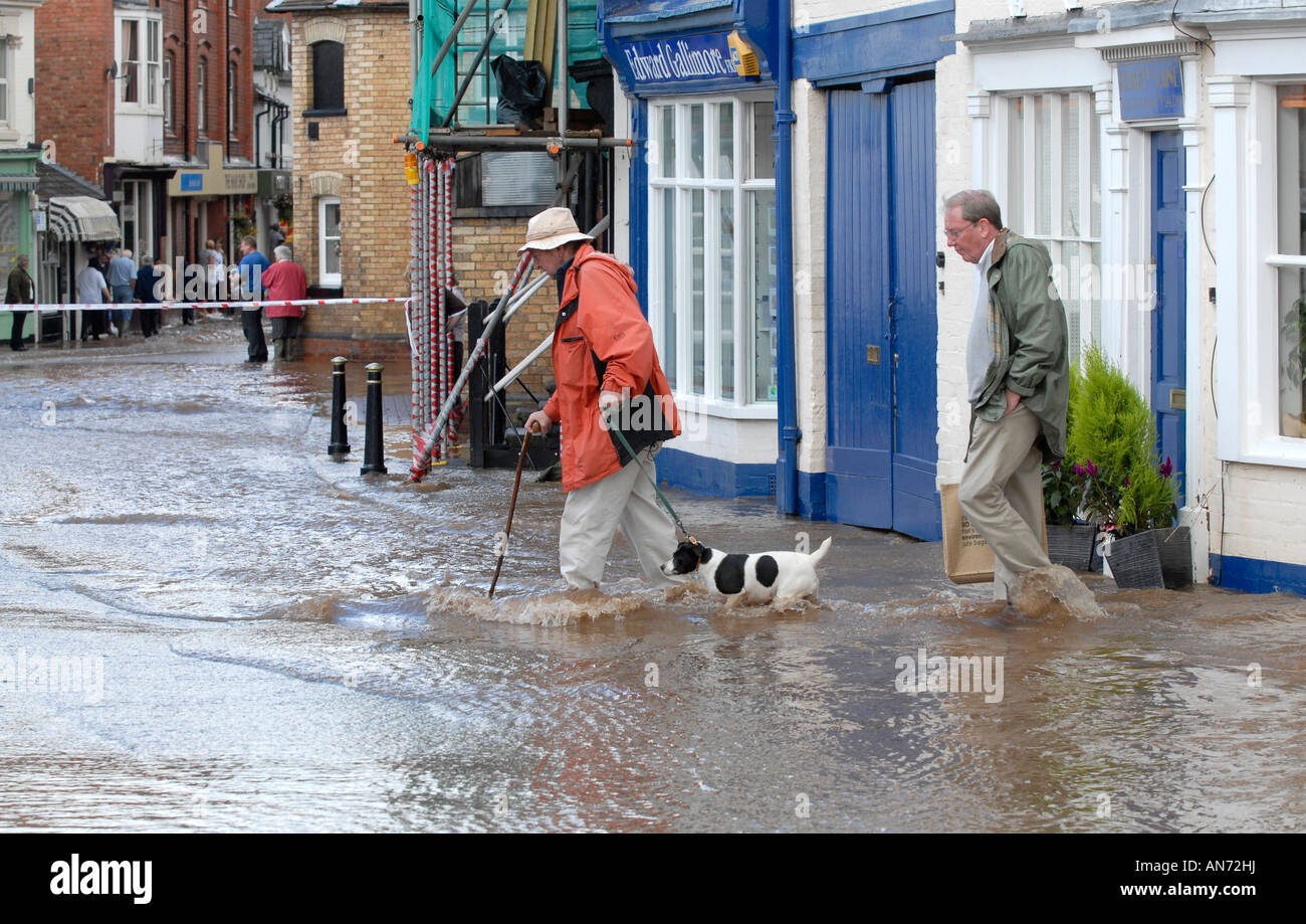 Mann über überfluteten Straße mit seinem Hund. Überschwemmungen in Tenbury Wells in Worcestershire Stockfoto