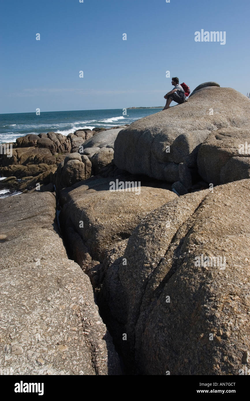 Männliche Figur saß auf felsigen Strand Stockfoto