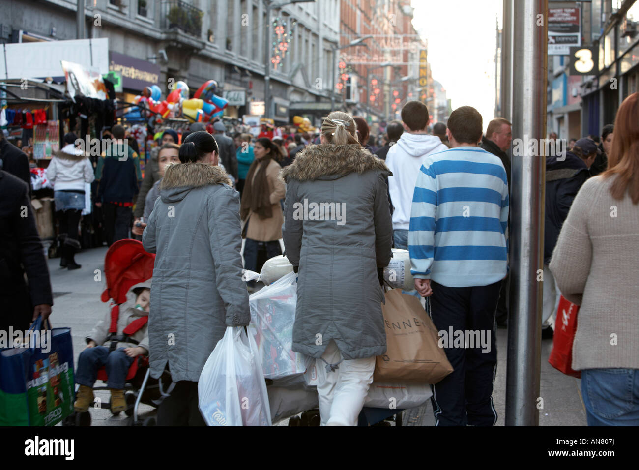 Frauen-Shopper mit Einkaufstüten schieben Kinderwagen durch schwere Menge auf Henry Street vor Weihnachten Dublin Republik von Irland Stockfoto