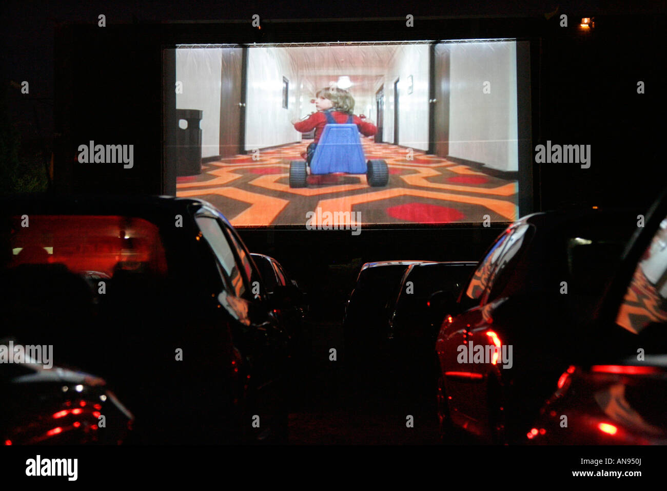 Autos in einem Laufwerk obwohl Kino in der Nacht beobachten, The Shining Stockfoto