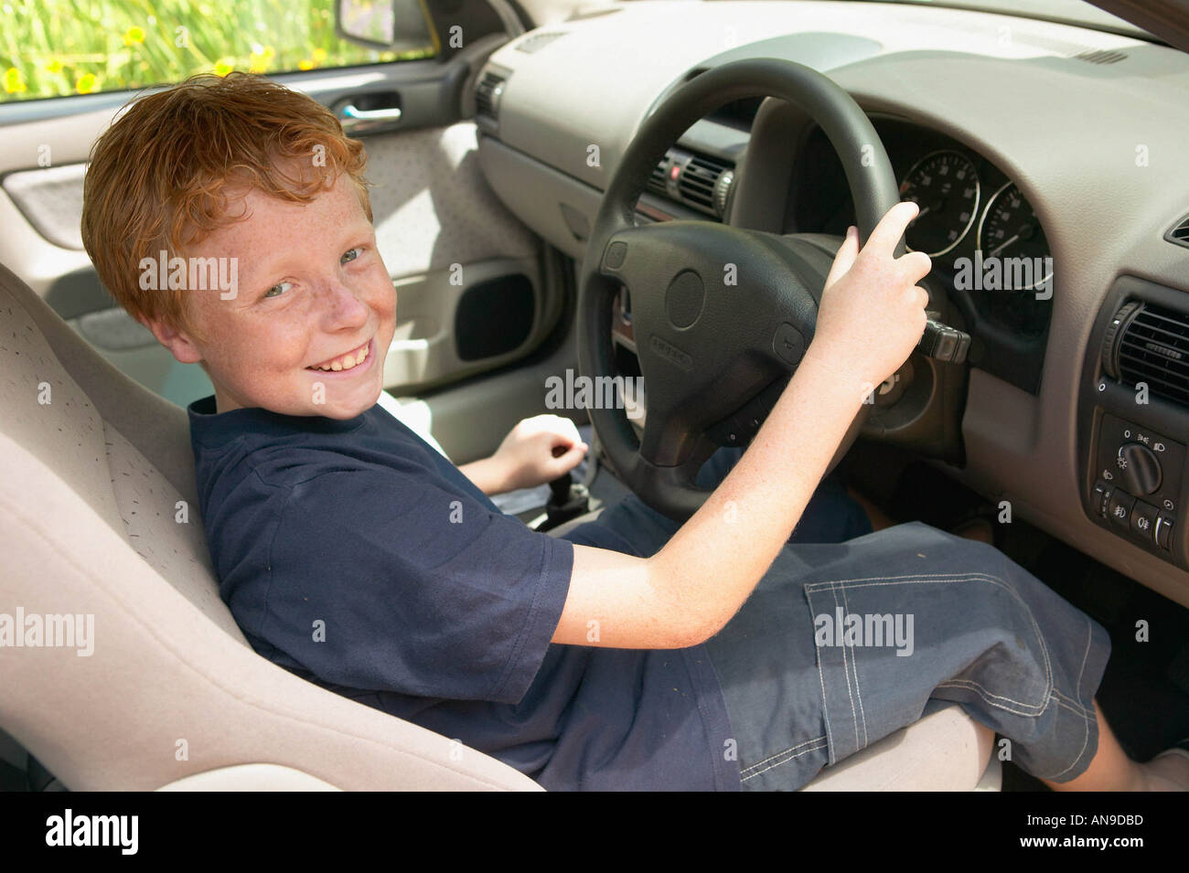 Lächelnde junge am Rad des Autos Stockfoto