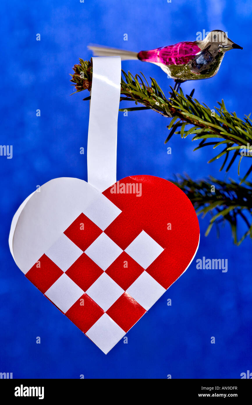 Glas-Vogel und gewebte Herzen am Weihnachtsbaum Stockfoto