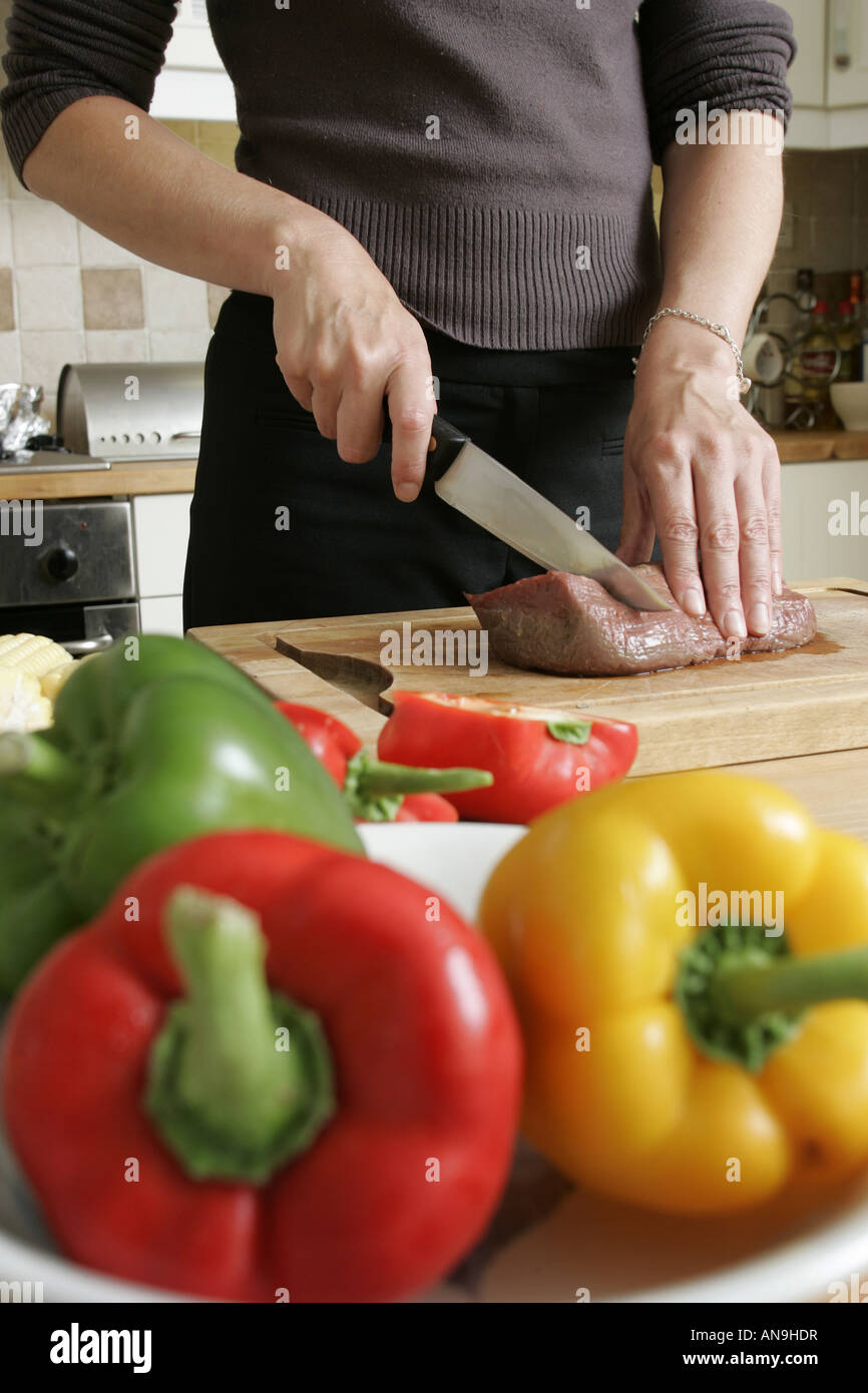 EINE JUNGE FRAU BEREITET EINE MAHLZEIT IN DER HEIMISCHEN KÜCHE. Stockfoto