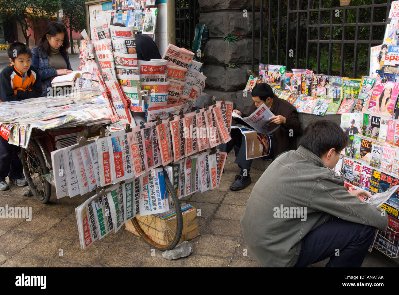 China-Chengdu Stadt Zentrum Straßenzeitung stehen auf einem Fahrrad mit Menschen lesen Stockfoto