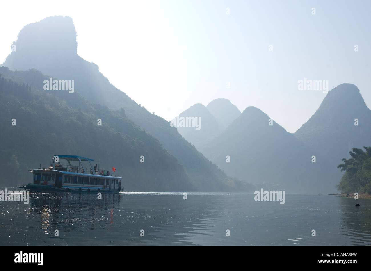 China-Guangxi Yuangshuo Touristenboot Kreuzfahrt auf dem Li-Fluss im Morgenlicht mit typischen Kalksteinspitzen in bkgd Stockfoto