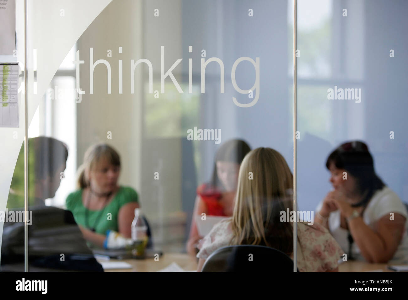 FÜNF MENSCHEN, DIE EIN TREFFEN HINTER GLAS IN EINER BÜROUMGEBUNG. Stockfoto