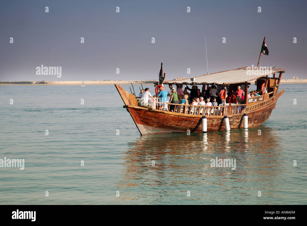 Seitenansicht eines traditionellen hölzernen Dhow flott mit einer Gruppe von Touristen an Bord, auf eine Kreuzfahrt, Abu Dhabi, VAE Stockfoto